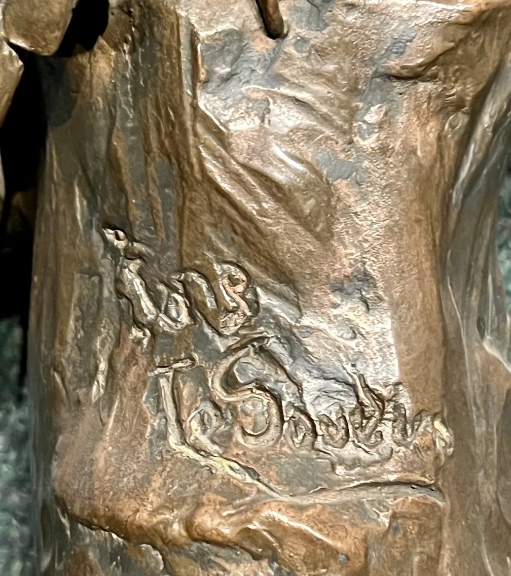 escultura antigua de bronce con detalles visibles firmada