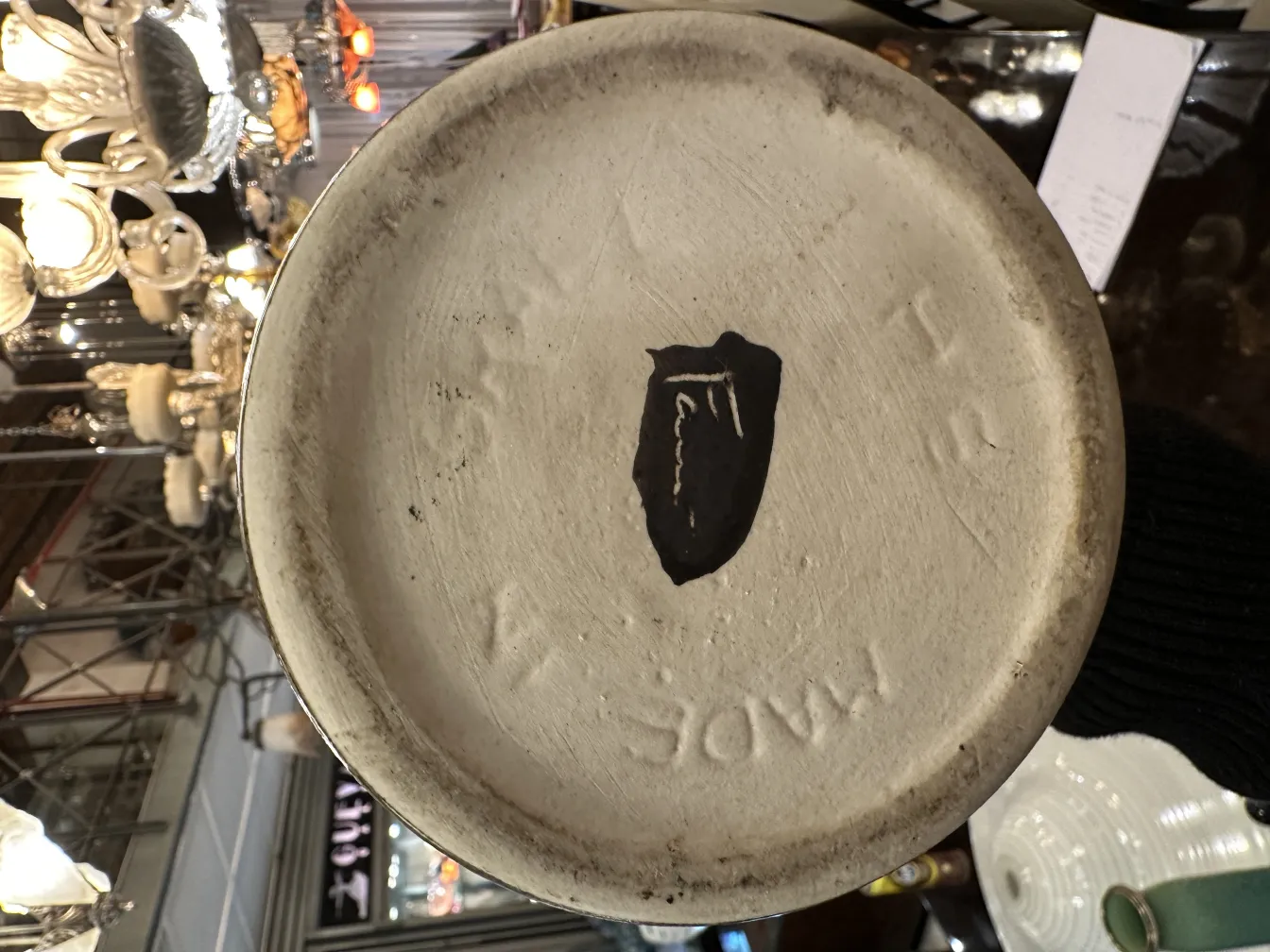 Base di ceramica antica decorativa con dettagli visibili e motivo, circondata da luci soffuse