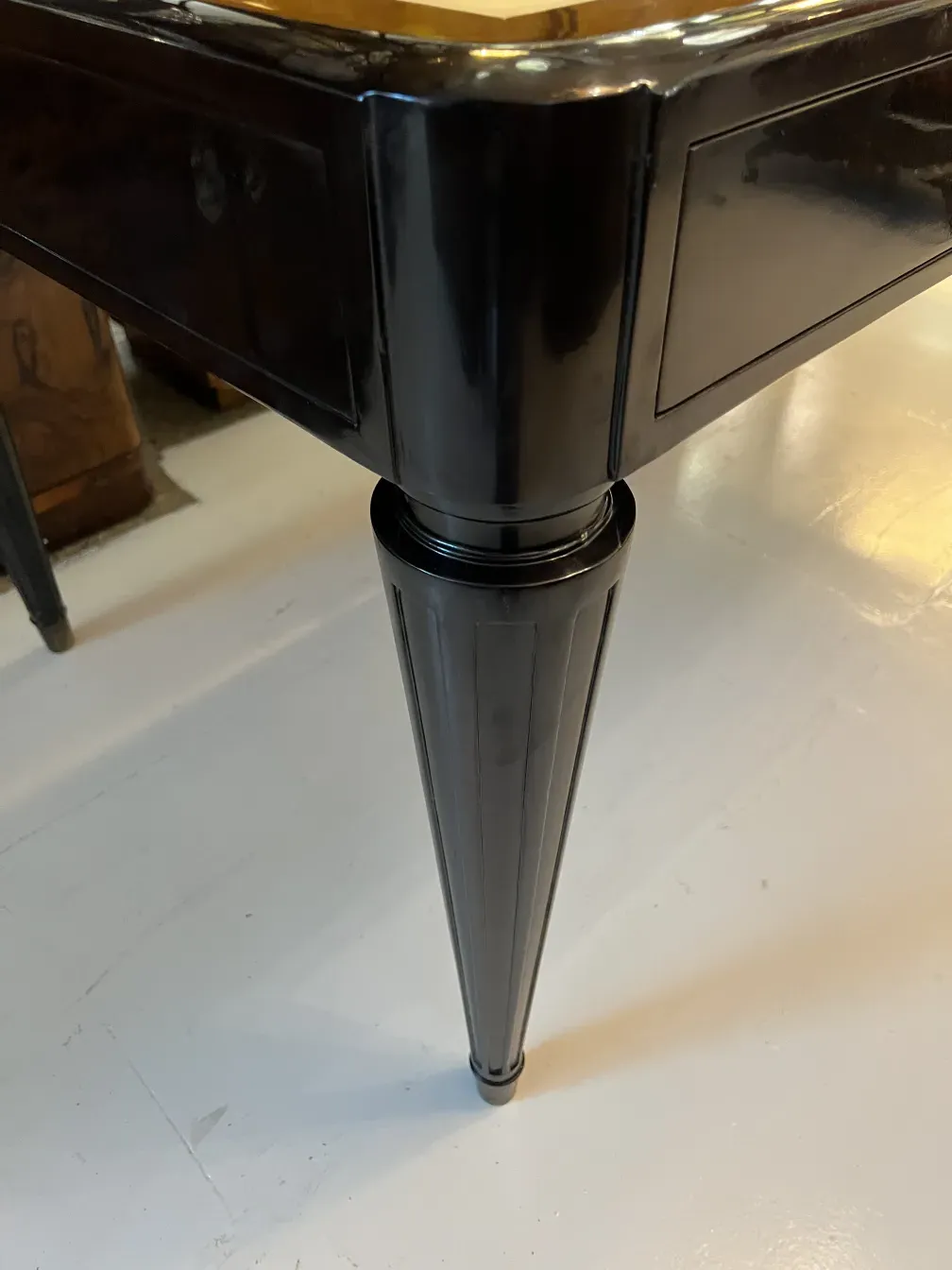 Dettaglio di una scrivania antica con un design elegante e una gamba stilizzata.