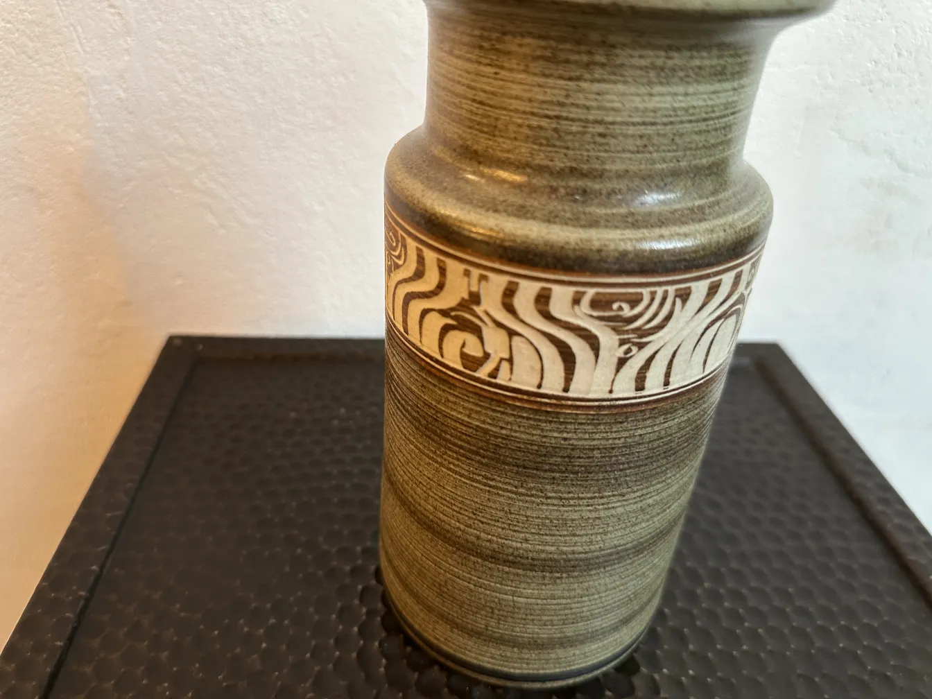 Vaso in ceramica antica con motivi unici su uno sfondo neutro.