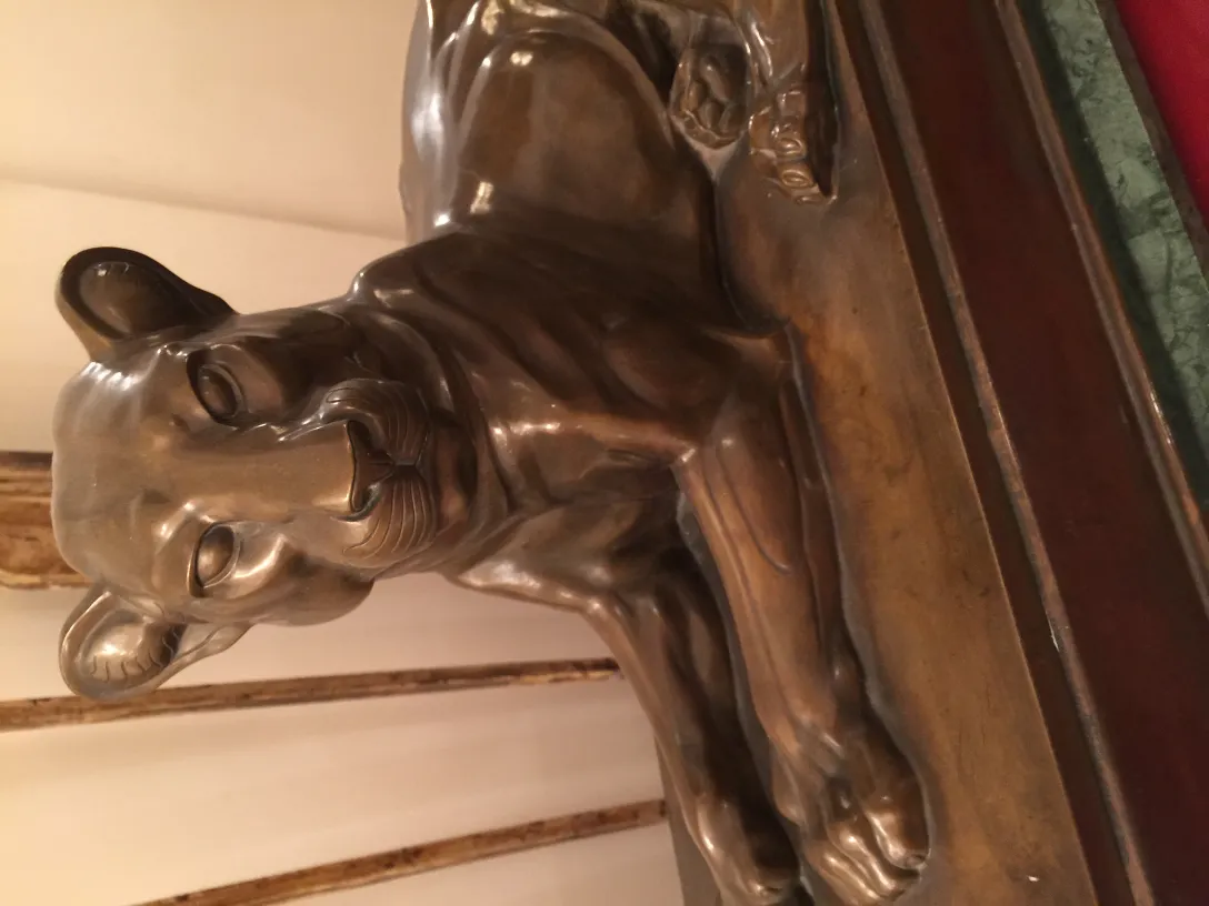 Scultura antica di un leone in posizione rilassata, dettagliata.