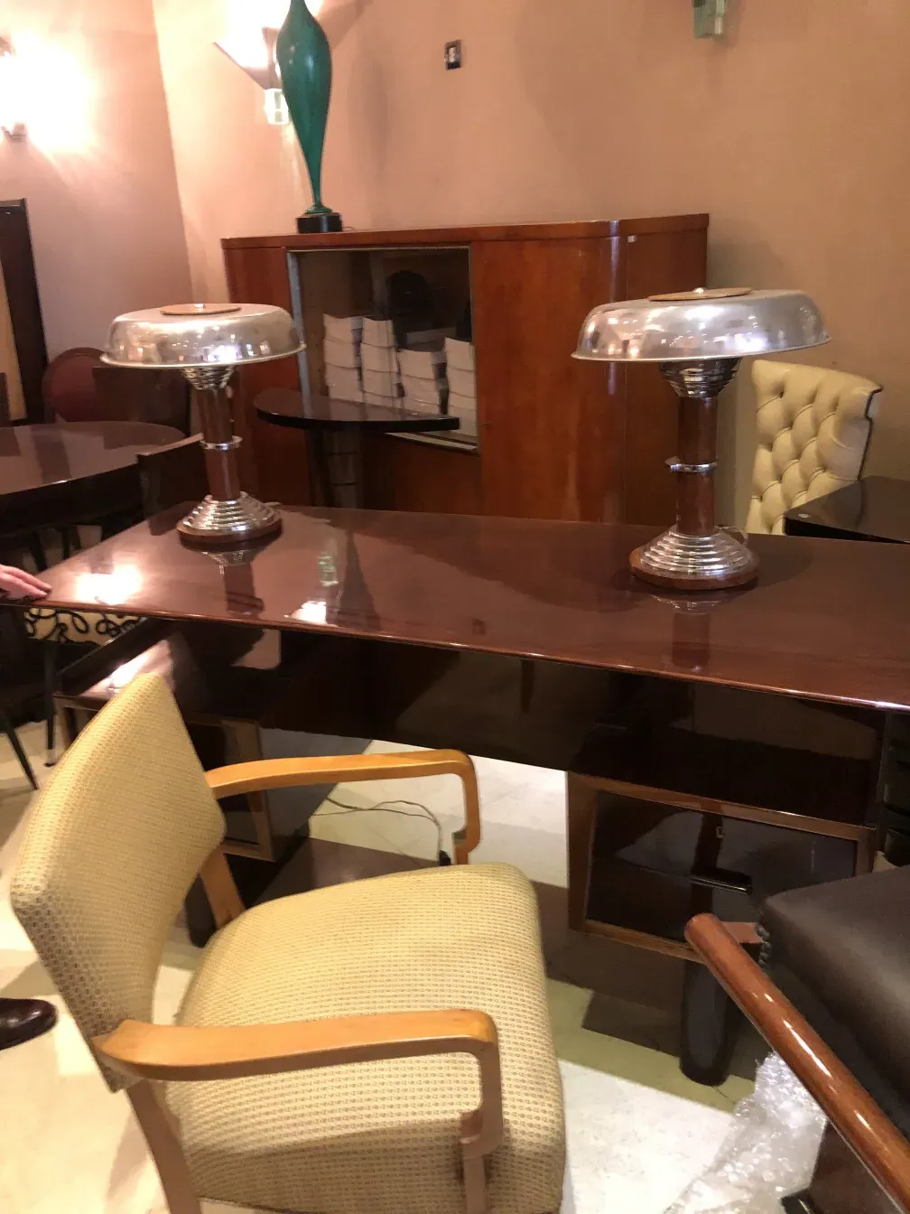 Blick auf einen antiken Schreibtisch mit silbernen Lampen und Stühlen in einem eleganten Ambiente.