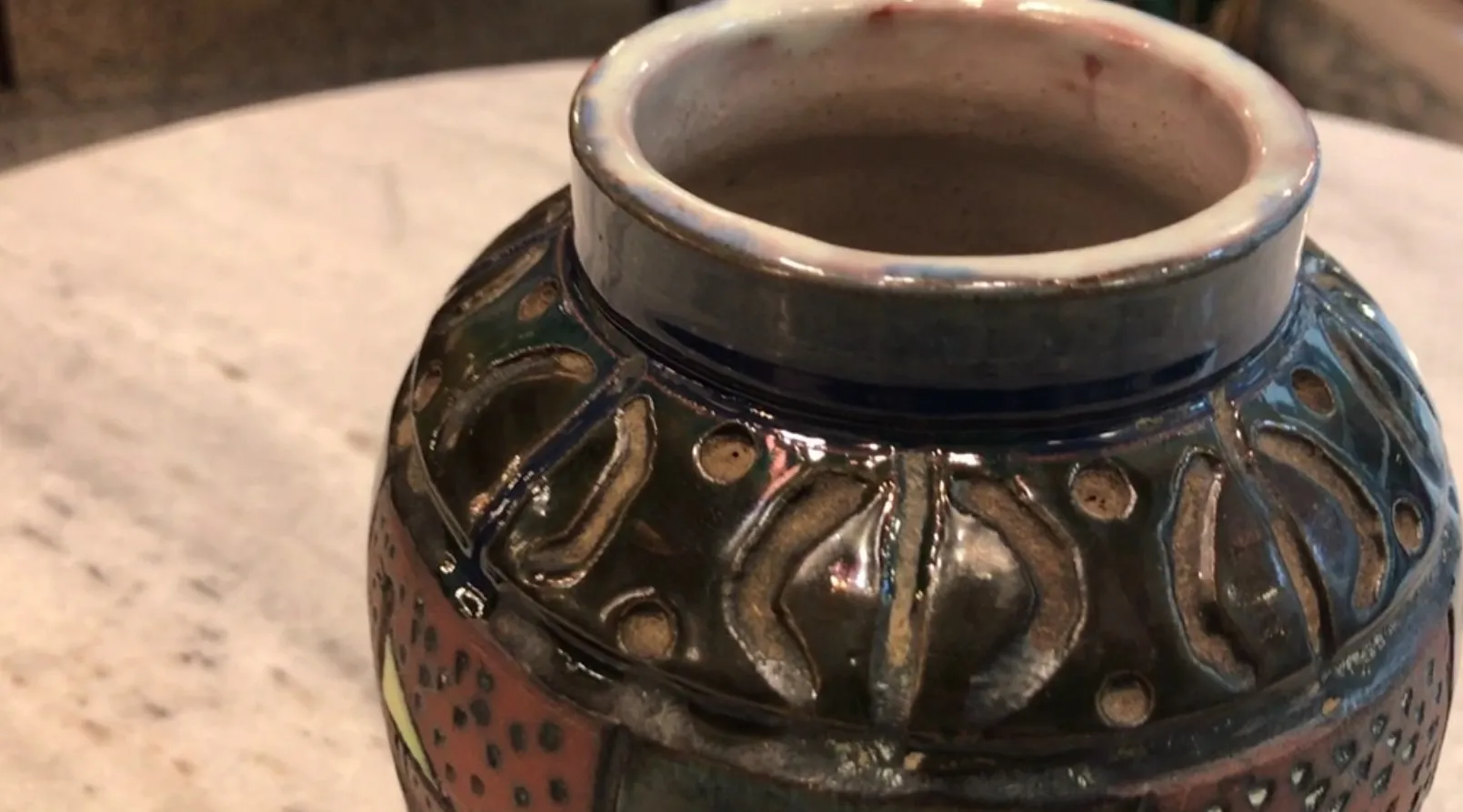 Vaso antigo de cerâmica com decorações coloridas e detalhes entalhados