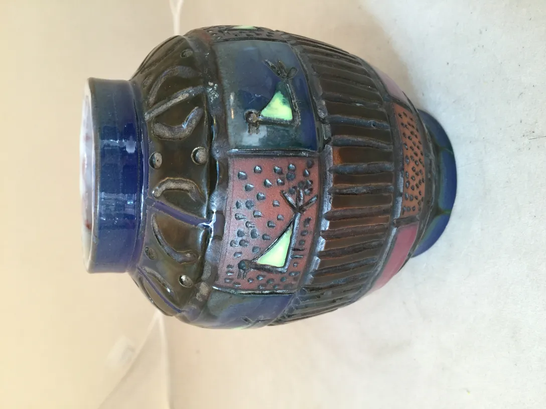 زهرية خزف قديمة مزخرفة بألوان زاهية وملمس مثير، مثالية للزينة.