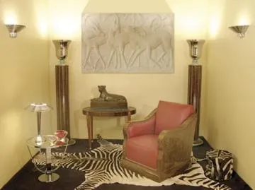 Escultura antigua de relieve sobre pared amarilla con sillón.