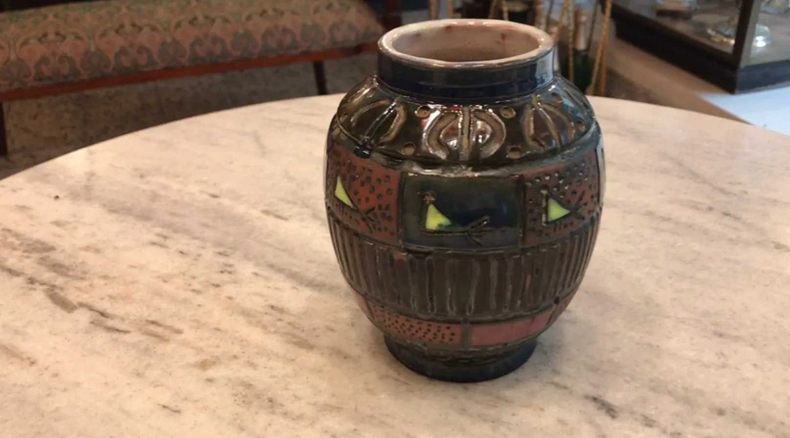 Vasija de ceramica antigua con diseño colorido y detalles decorativos