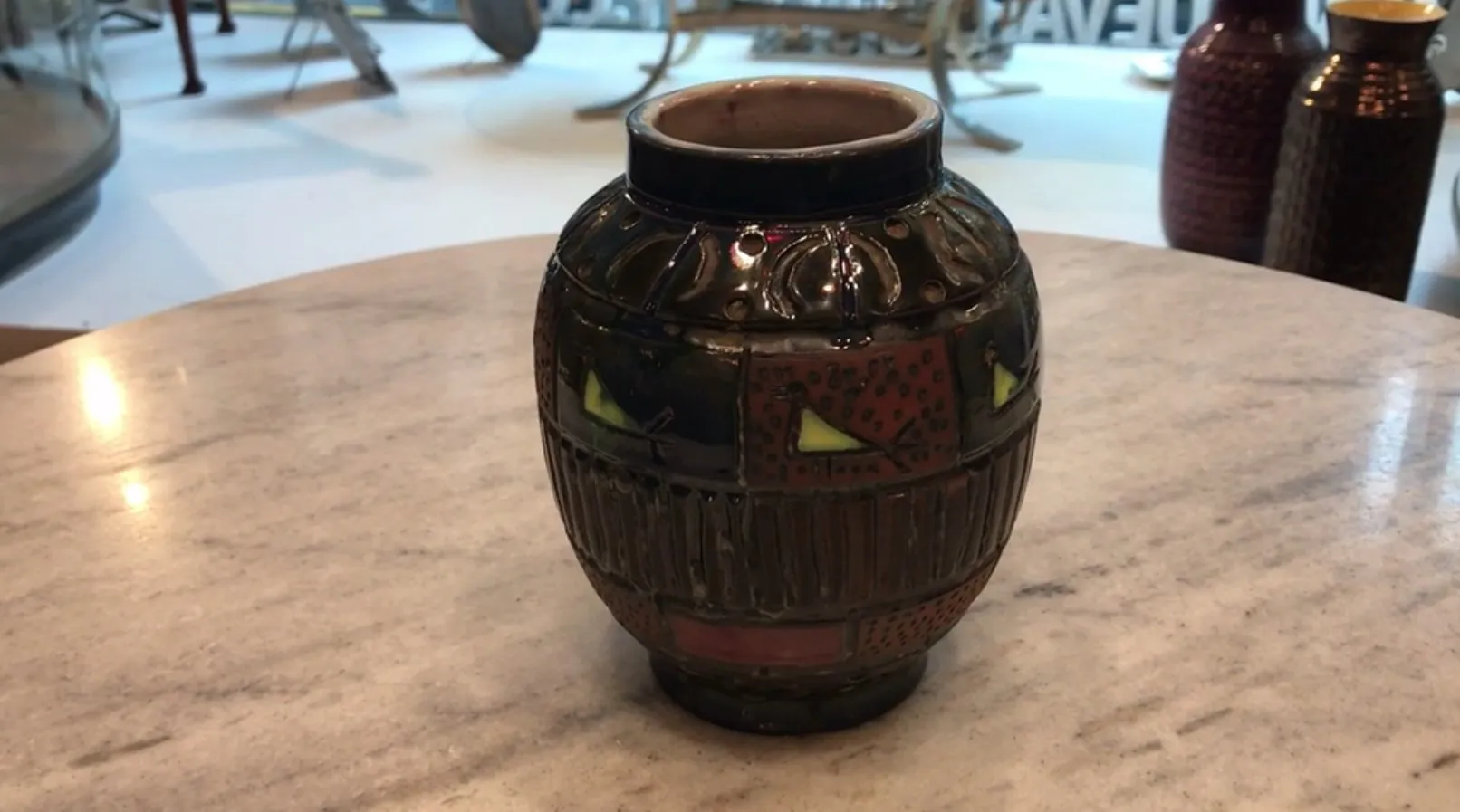 Ceramica decorativa antica in tonalità scure e colori vivaci, con disegni unici.