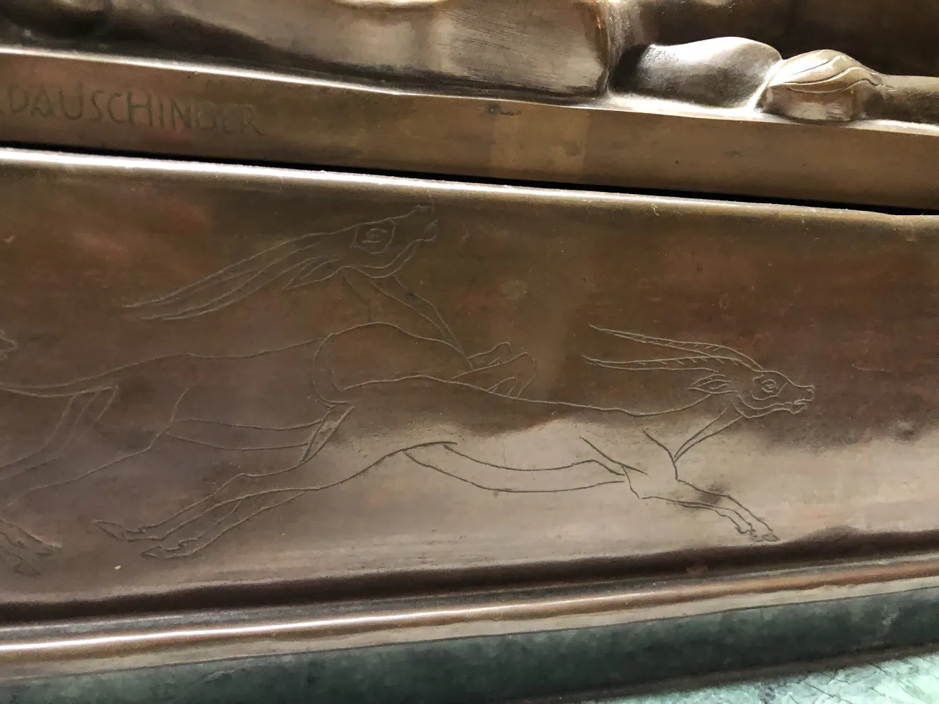 escultura antigua con grabados de animales corriendo en la base