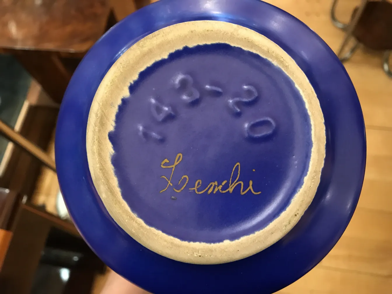 Oggetto d'arte in ceramica antica con base blu, dettagli dorati e firma visibile.