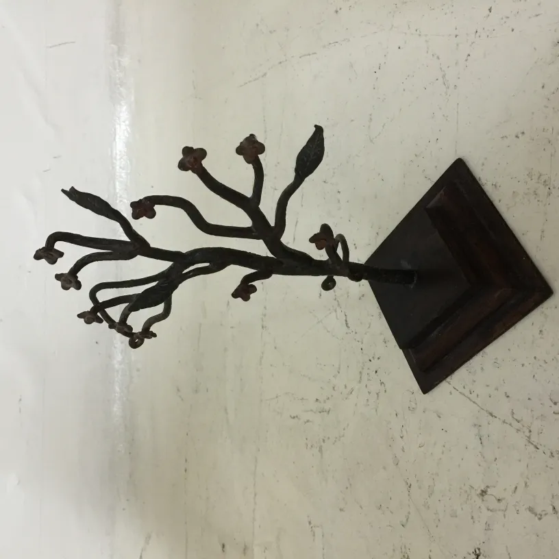 escultura antiga de um ramo em uma base com flores