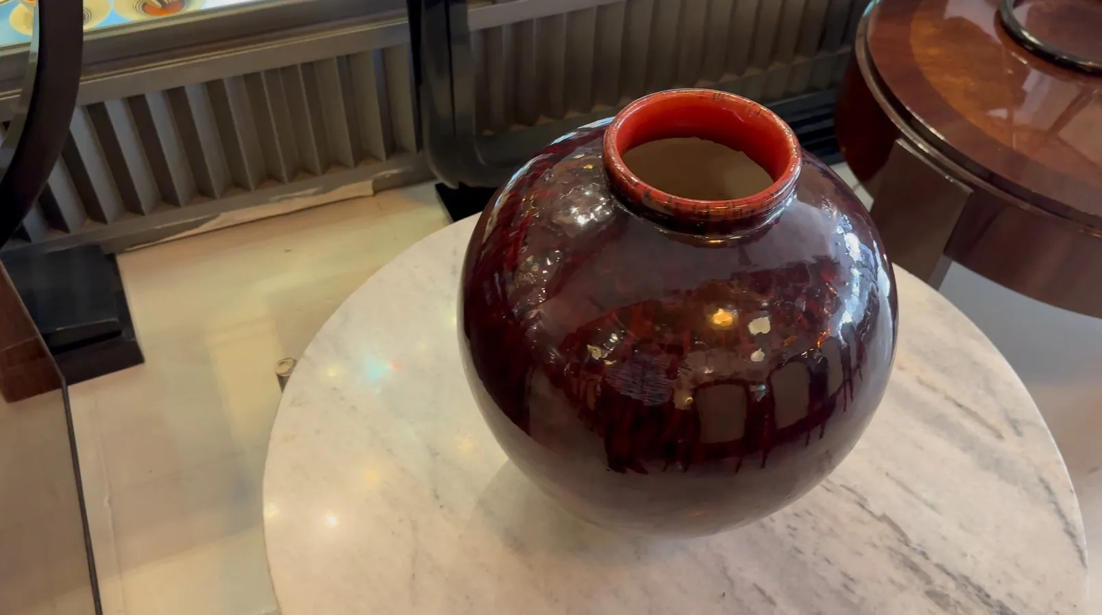 白いテーブルの上にある古い赤い陶器の装飾品、光沢のある仕上げで。