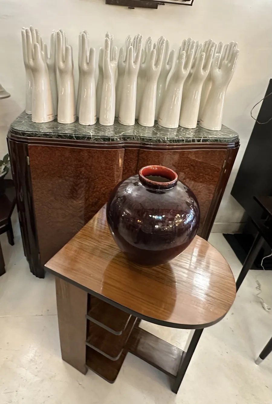 Vase ancien en céramique de couleur sombre sur une table triangulaire, entouré de décorations