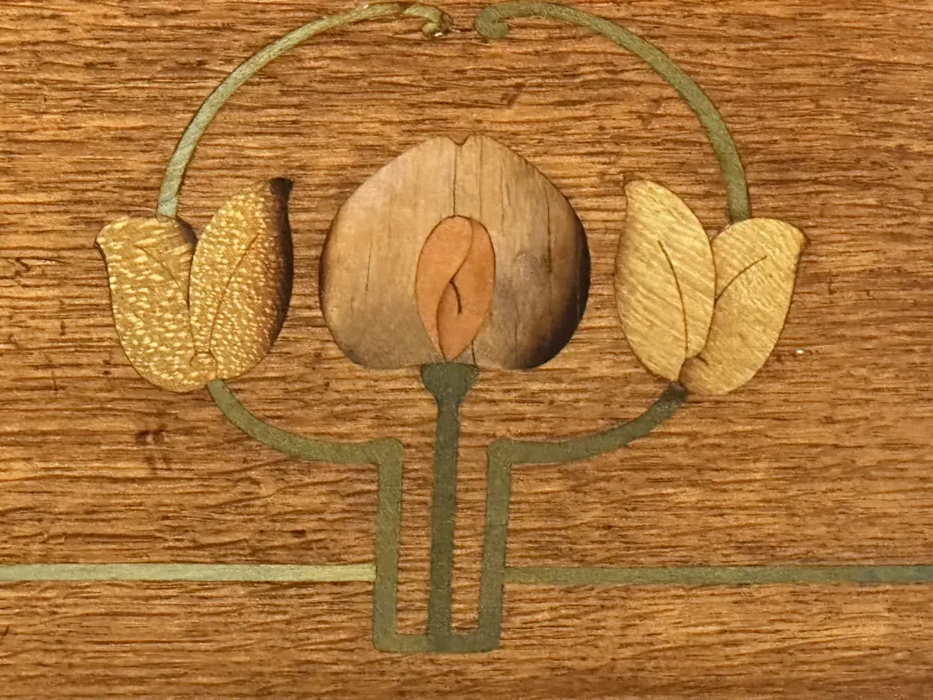 पुराने डेस्क का विवरण जिसमें गर्म रंगों में पत्तियों की सजावट है.