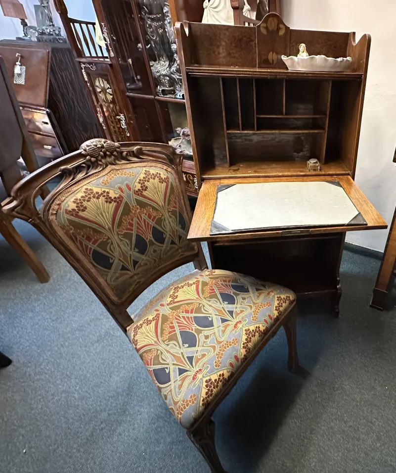 Bureau ancien accompagné d'une chaise décorée et d'une étagère.