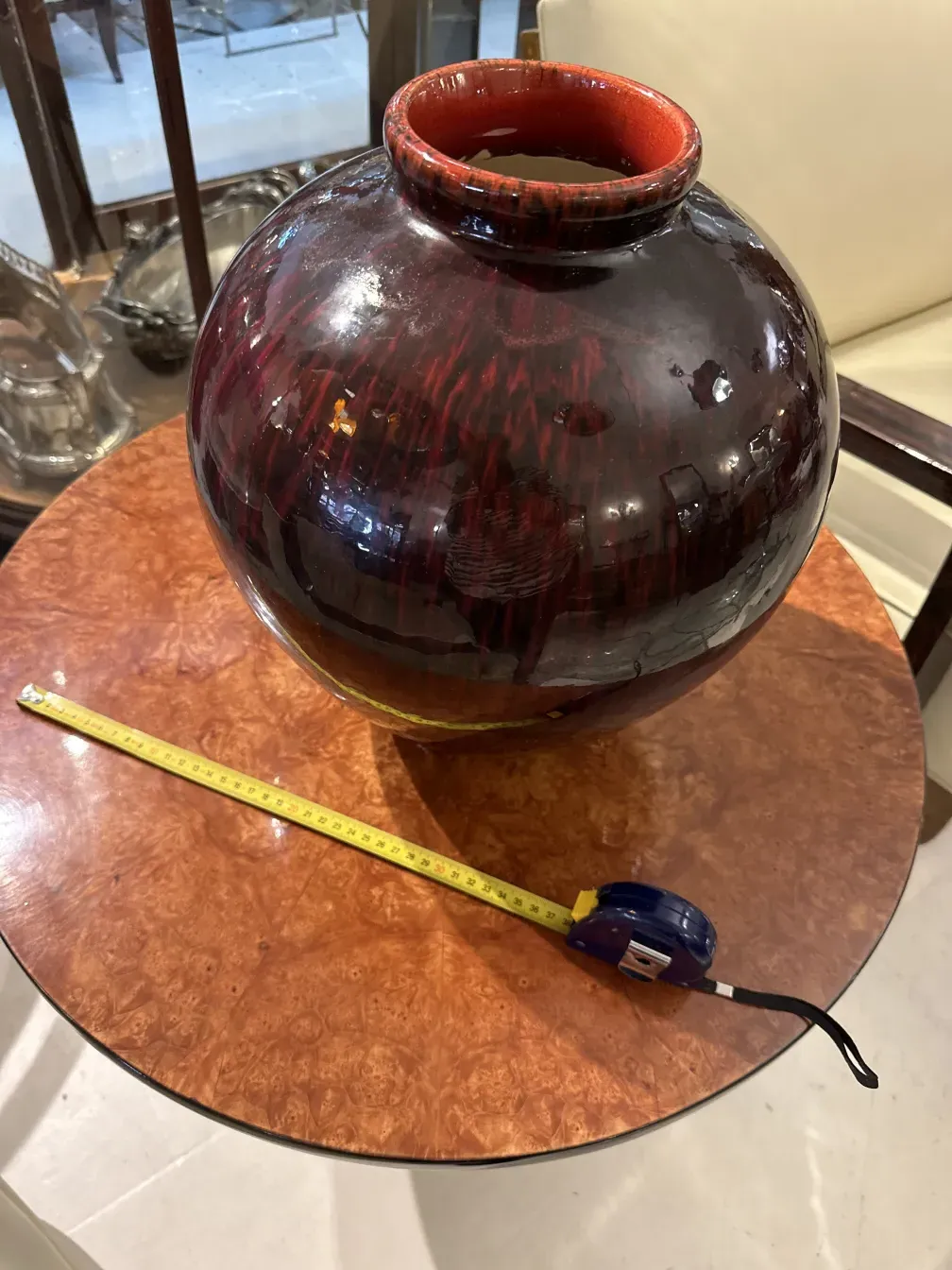 Vase en céramique antique avec une finition brillante, décoré de tons rougeâtres.