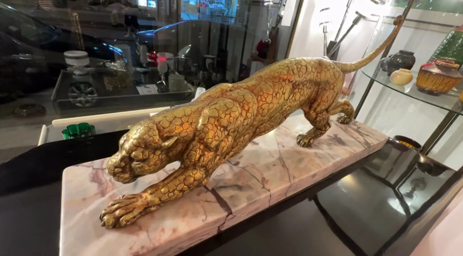 escultura antiga de um felino dourado, ambiente moderno e vitrine