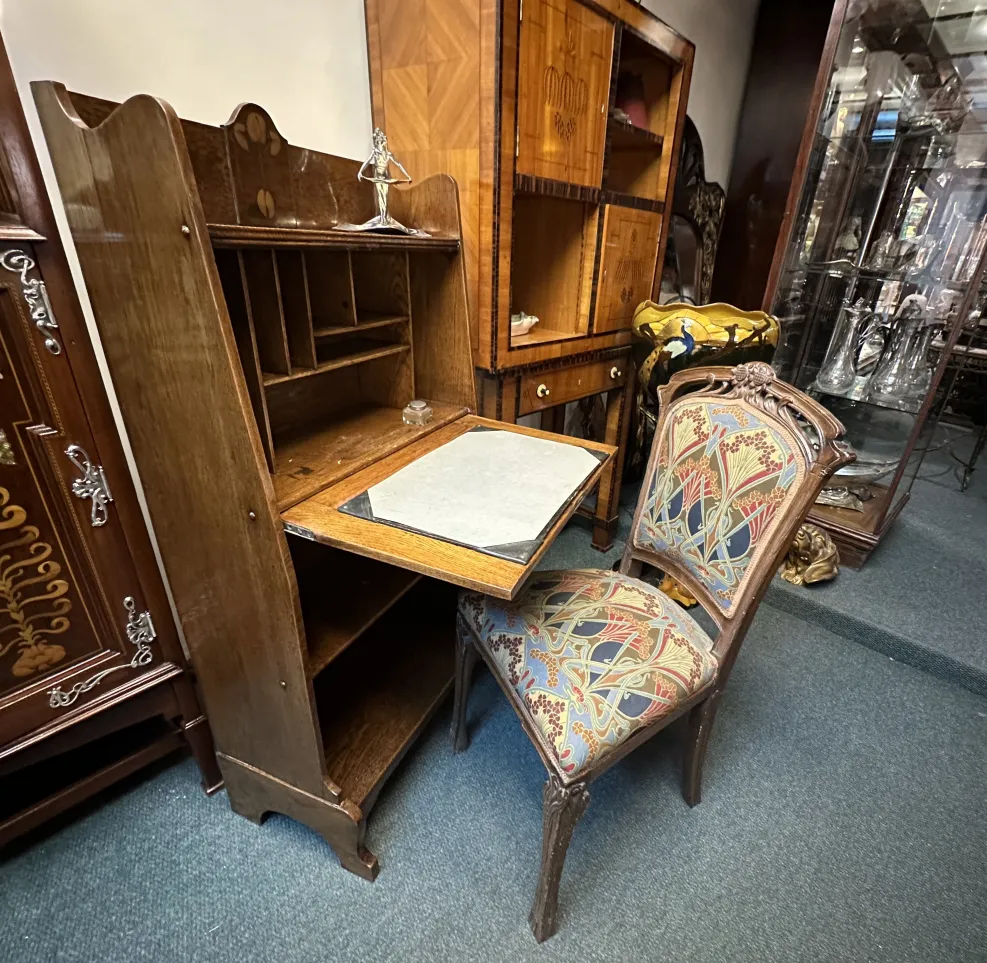 Antique wooden desk with shelf and colorful chair.