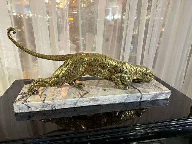 escultura antiga de felino em pose dinâmica sobre base