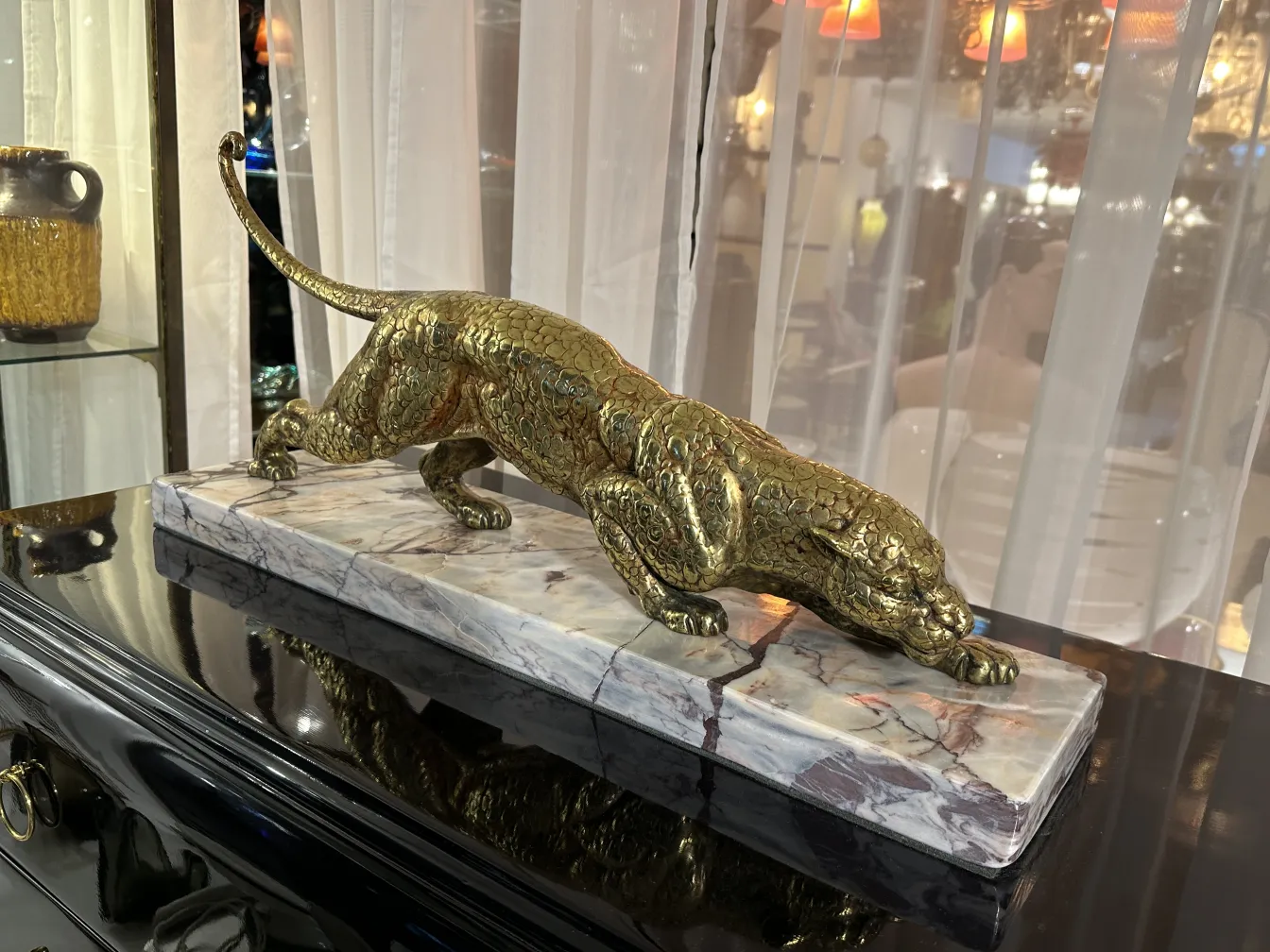 escultura antigua de un felino dorado en base de mármol