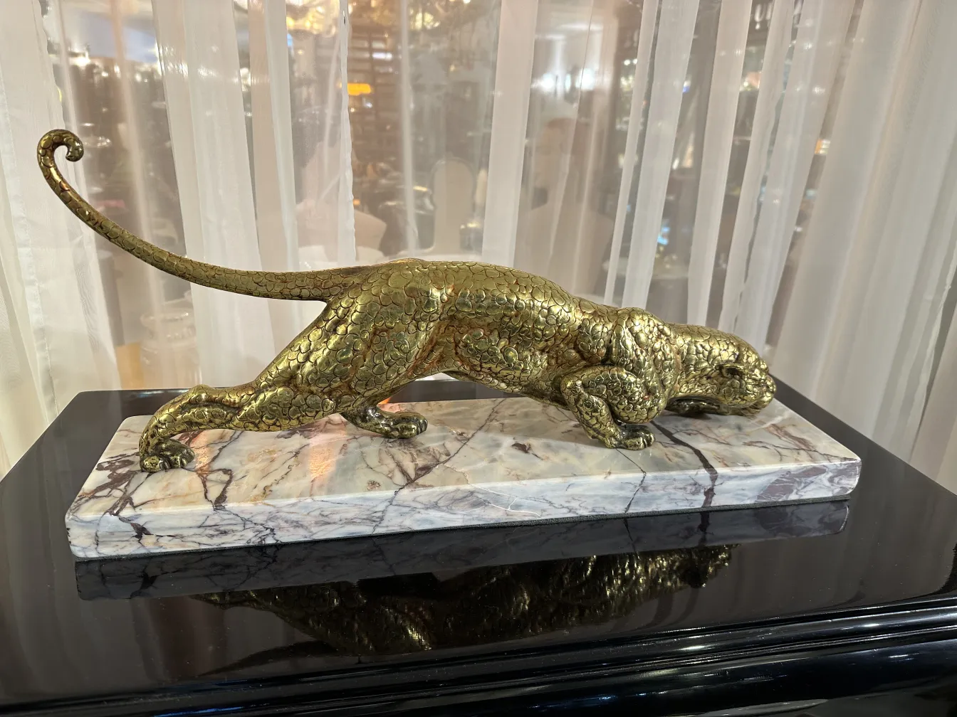 Escultura antiga de um animal em movimento sobre base marmorizada