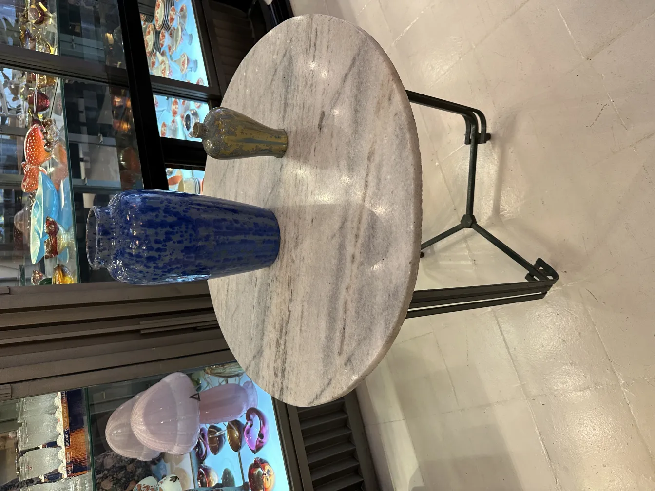 古董陶瓷花瓶放在圆形桌子上，背景五彩缤纷