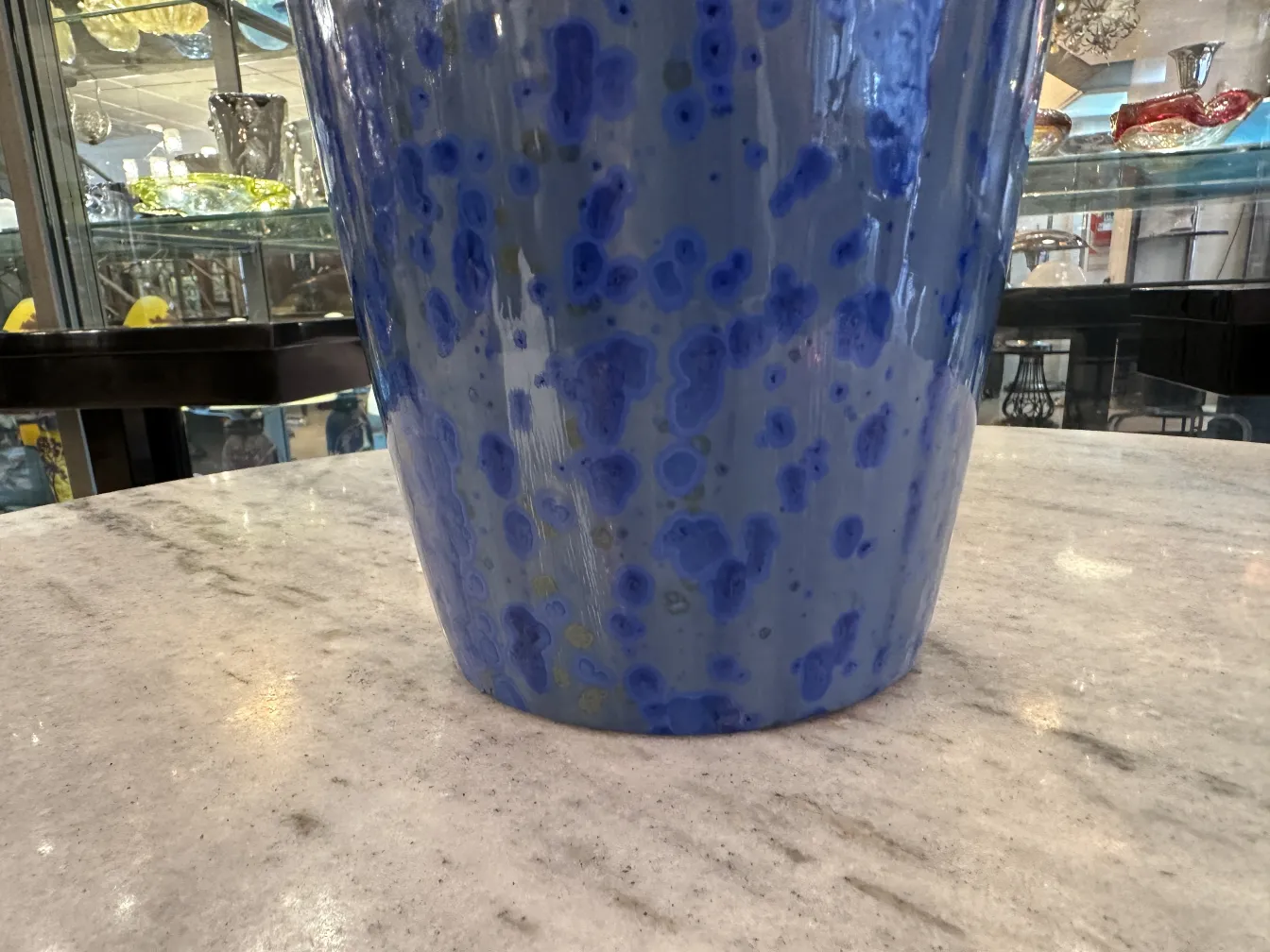 Ceramica antigua de color azul con patrones visibles, en un ambiente de antigüedades.