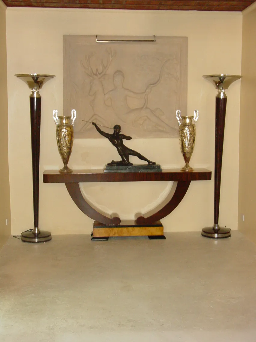 escultura preta em destaque numa mesa com vasos dourados