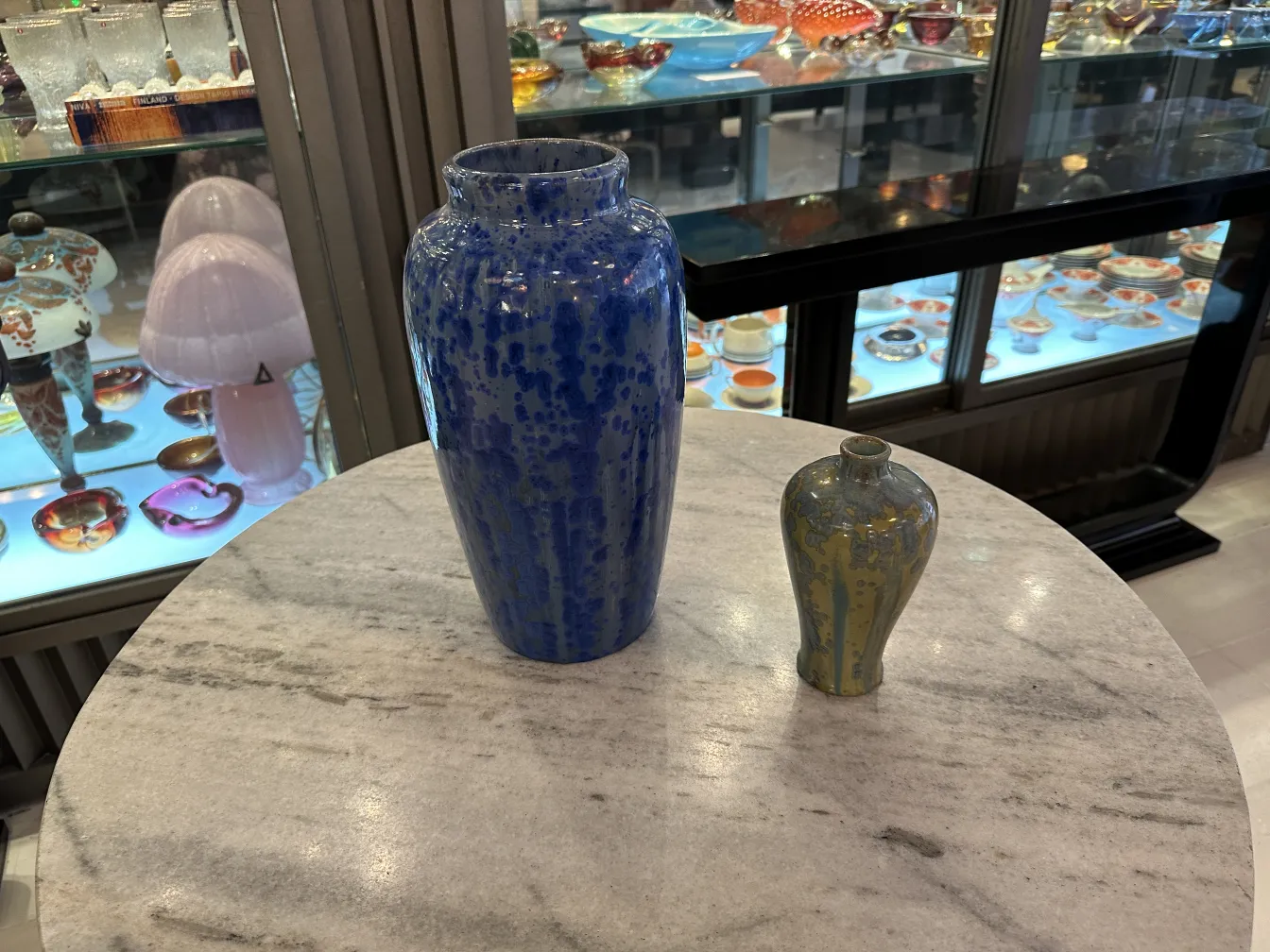 Deux vases anciens en céramique, un bleu et un vert, sur une table.