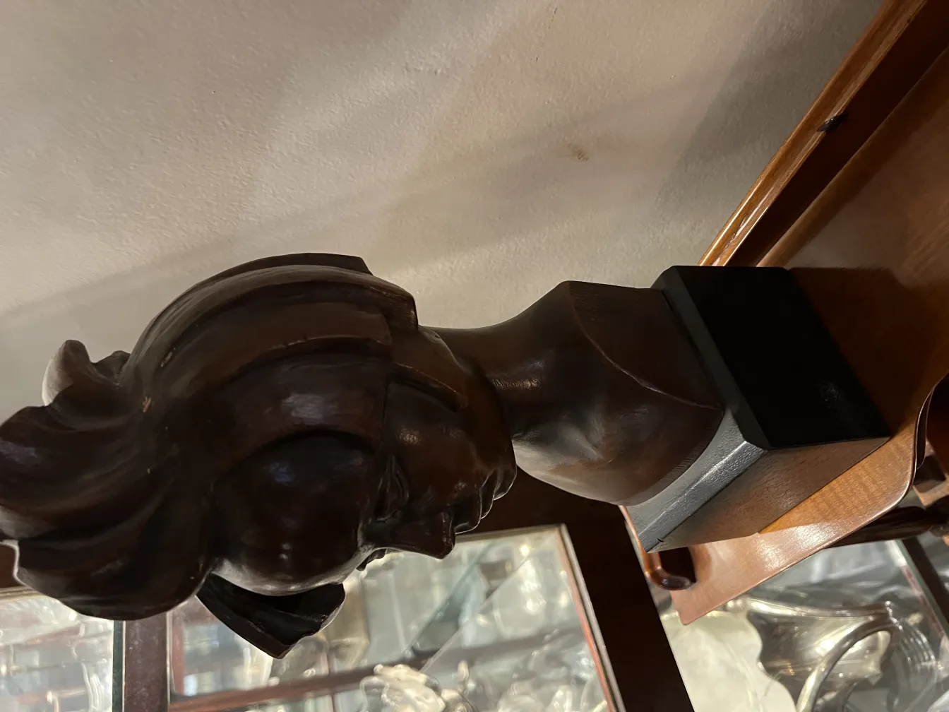 Escultura antigua de retrato en madera con detalles finos, fondo elegante.