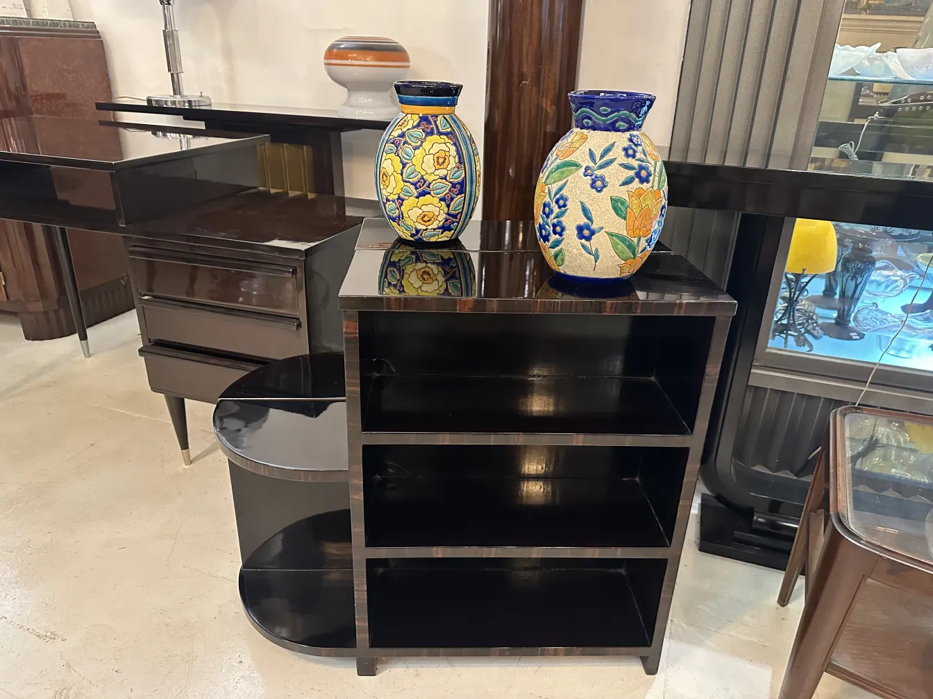 Dois vasos de cerâmica decorativa antiga com flores coloridas em um mobiliário preto brilhante, ambiente elegante