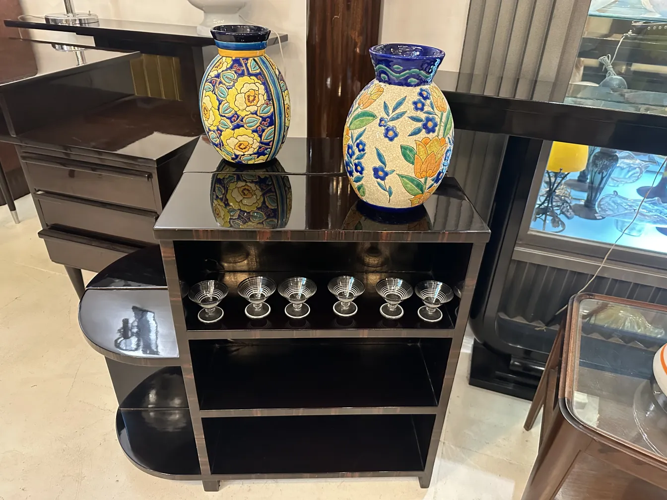 Deux vases anciens en céramique décorative sur une étagère noire avec des motifs floraux.