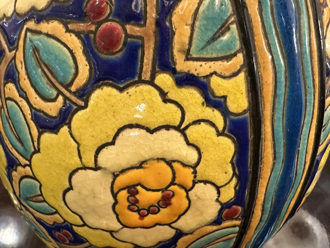 Céramique antique avec décoration florale colorée en jaune et bleu sur fond bleu clair.