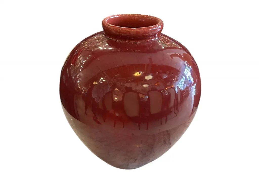 Vase en céramique ancienne en forme de globe rouge brillant.