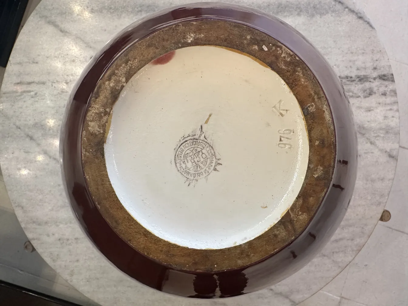 Vue de dessus d'un ancien bol en céramique avec un glaçage brun, sur une surface en marbre.