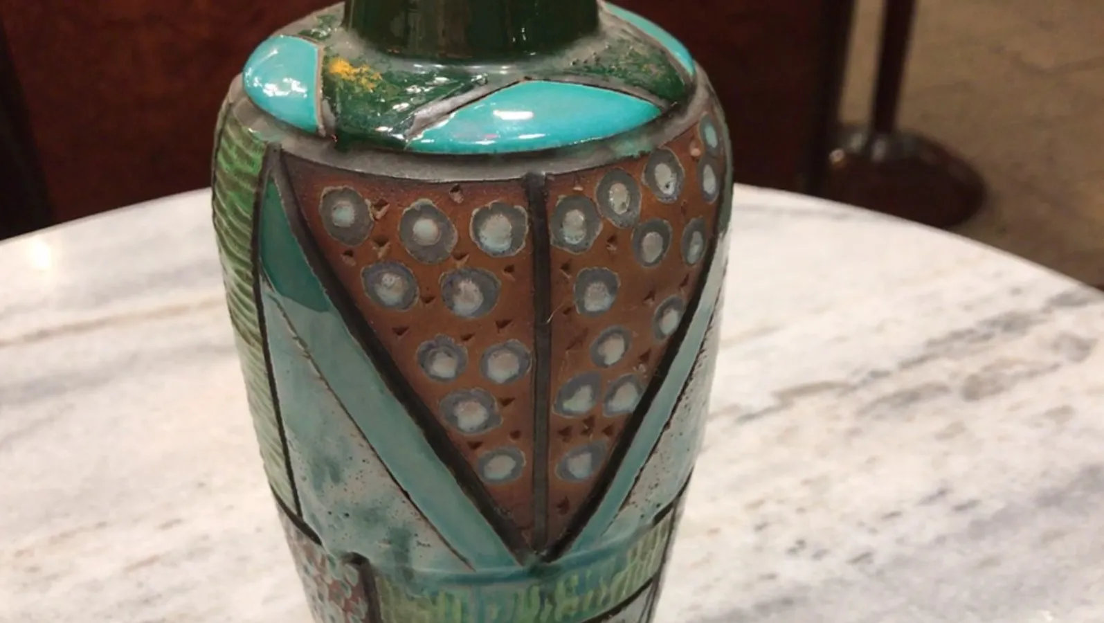 Cruche en céramique ancienne avec des décorations colorées et des motifs géométriques.