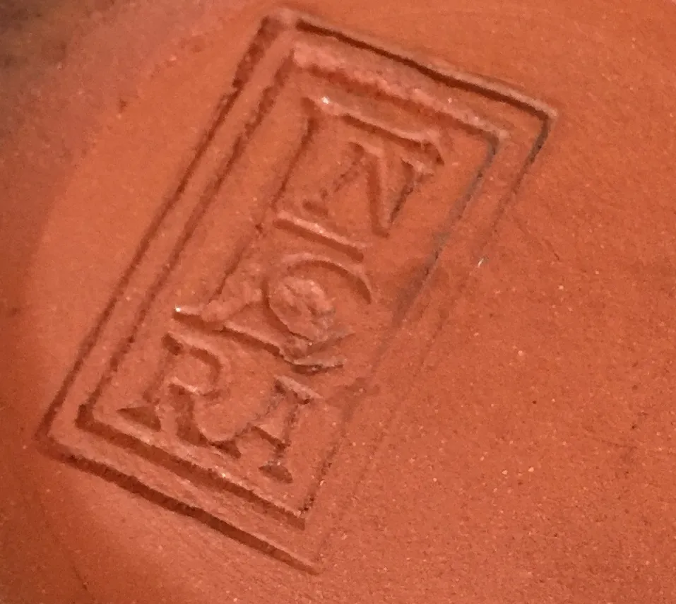 Antica ceramica con incisione, colore terracotta, sfondo liscio.