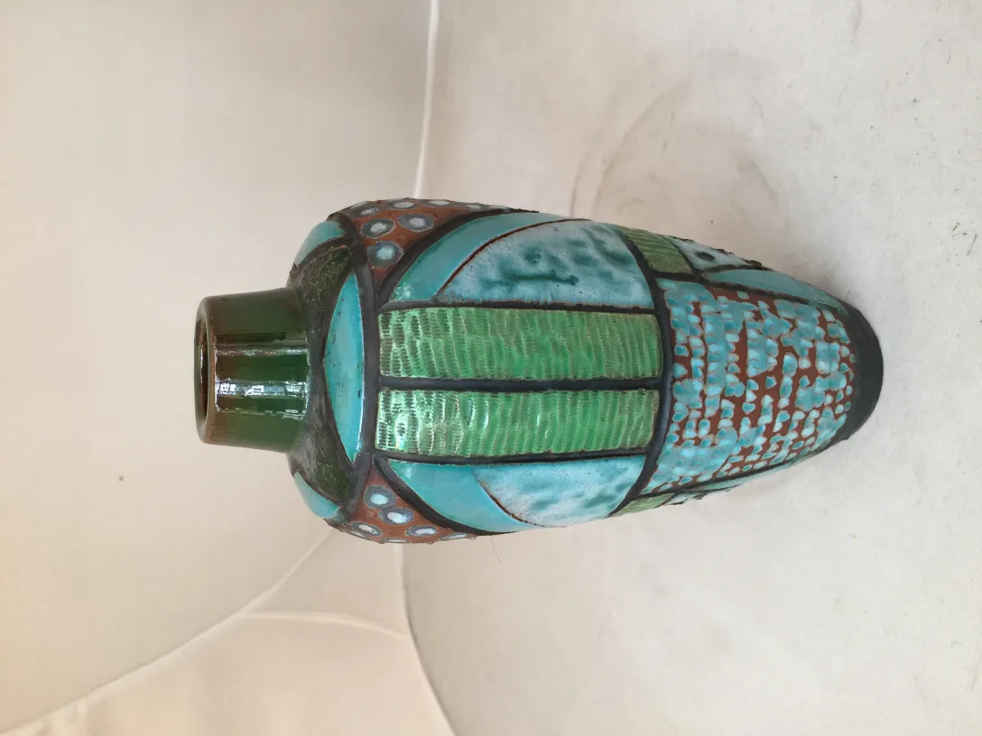 Antiga cerâmica decorativa em tons verdes e azuis, com formas distintas.