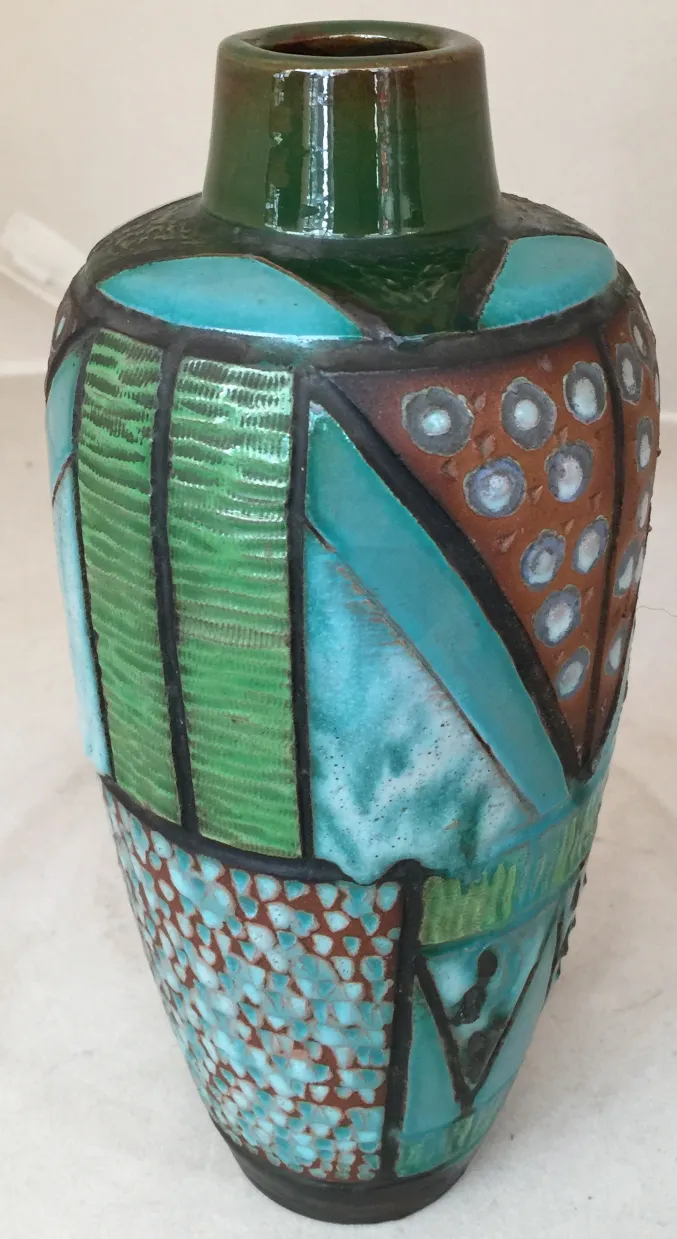 Vase en céramique ancien avec des motifs colorés et des formes géométriques.
