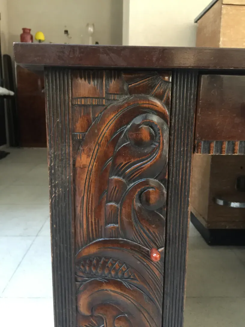 Scrivania antica in legno con dettagli in rilievo intricati, atmosfera calda.