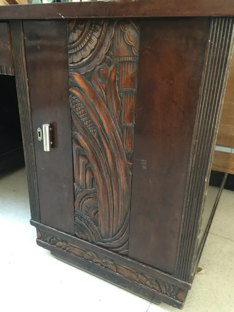 Antiker Schreibtisch mit schönen Schnitzereien, in klassischer Umgebung. Zeigt detailreiche Handwerkskunst.