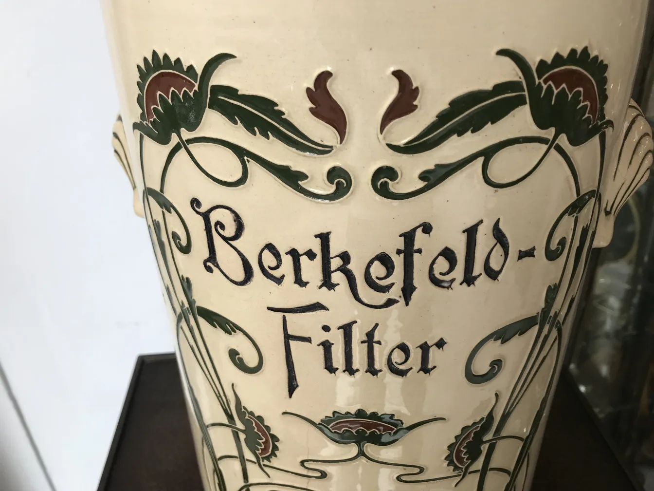 Antique ceramic with light background and floral design in green and red.