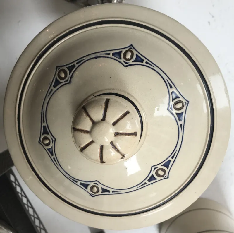 Tampa de cerâmica antiga em forma circular com detalhes azuis, elegante e decorativa.