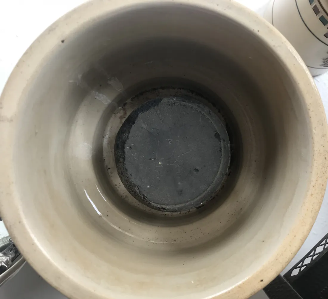 Antique light-colored ceramic bowl with dark interior, bright ambiance.