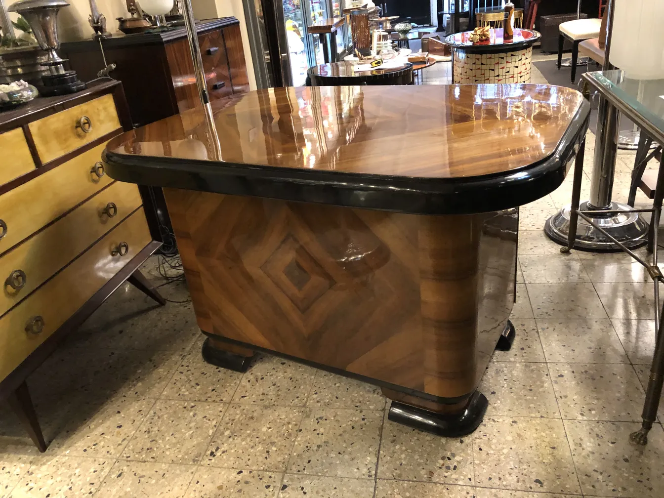 Bureau ancien avec surface brillante et finition élégante, entouré de meubles vintage.