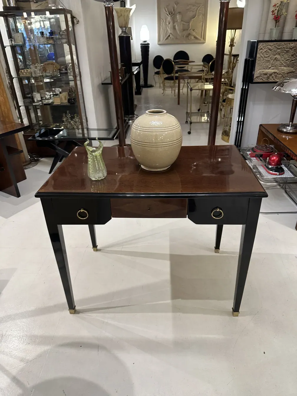 Antique desk featuring black details with a vase on top.