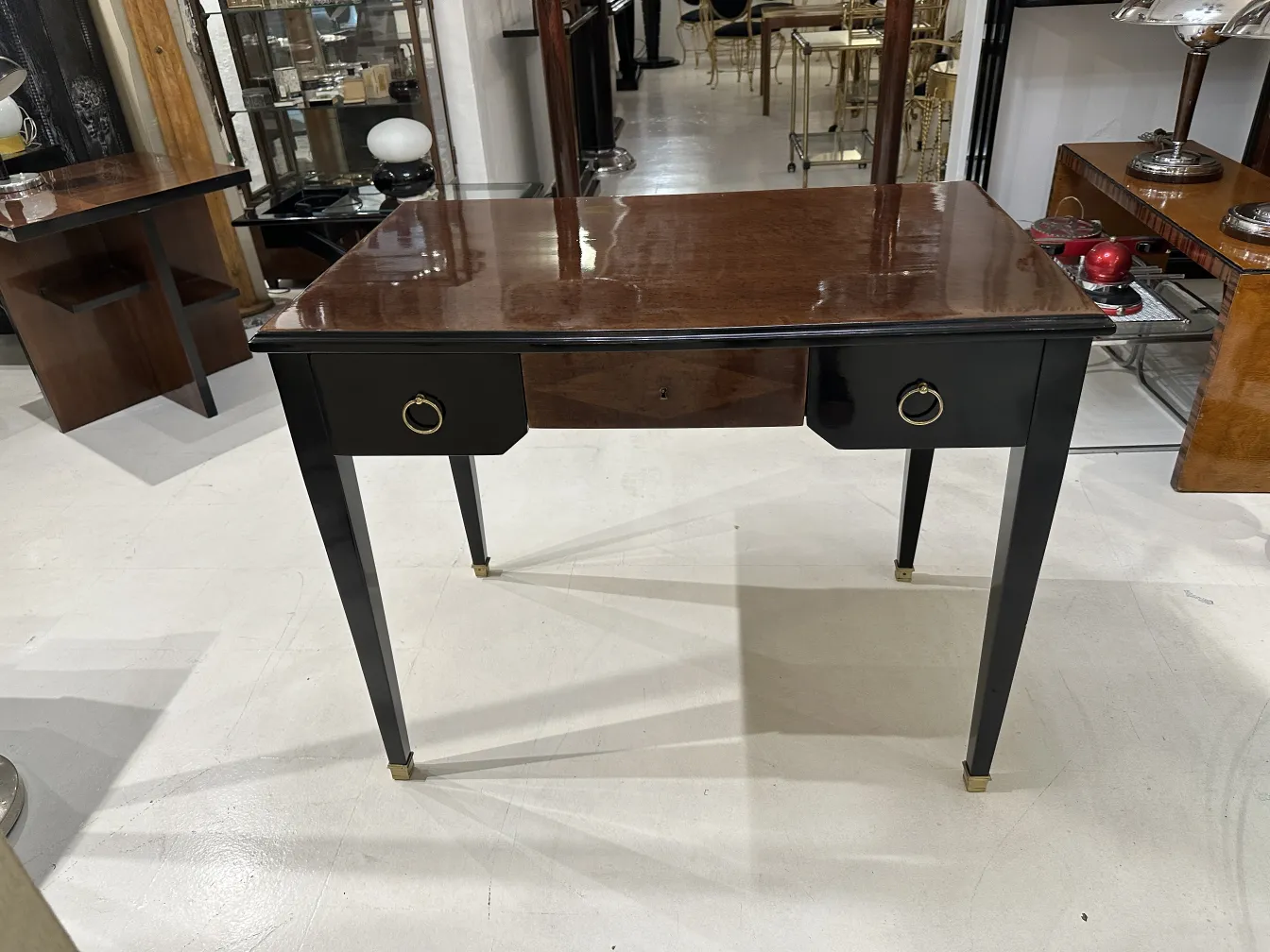 antiker schreibtisch mit glänzender oberfläche, vorderer schublade und anderen möbeln im hintergrund