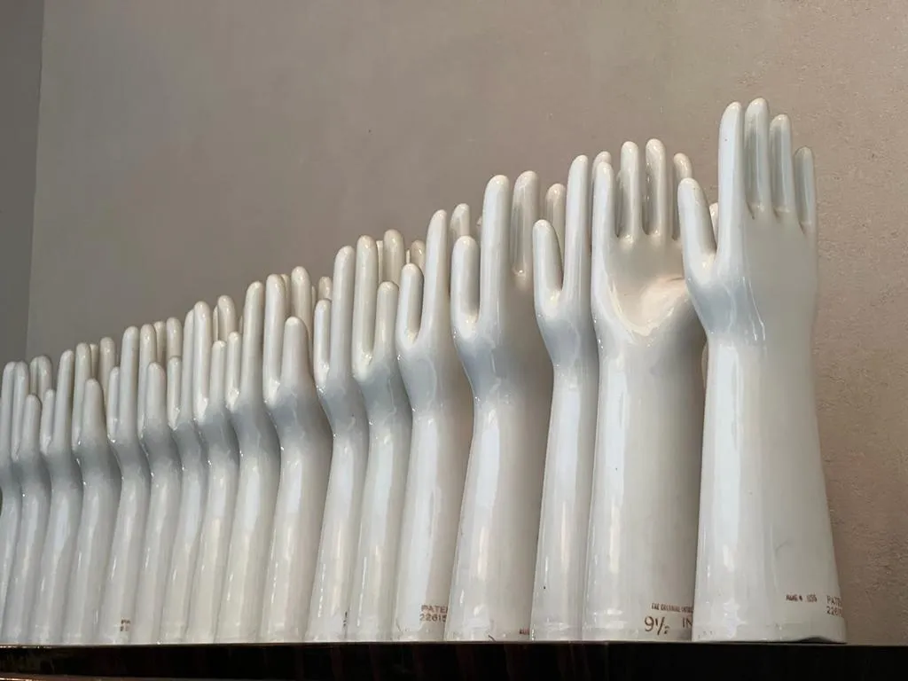 Antique white ceramic hands displayed on shelf.