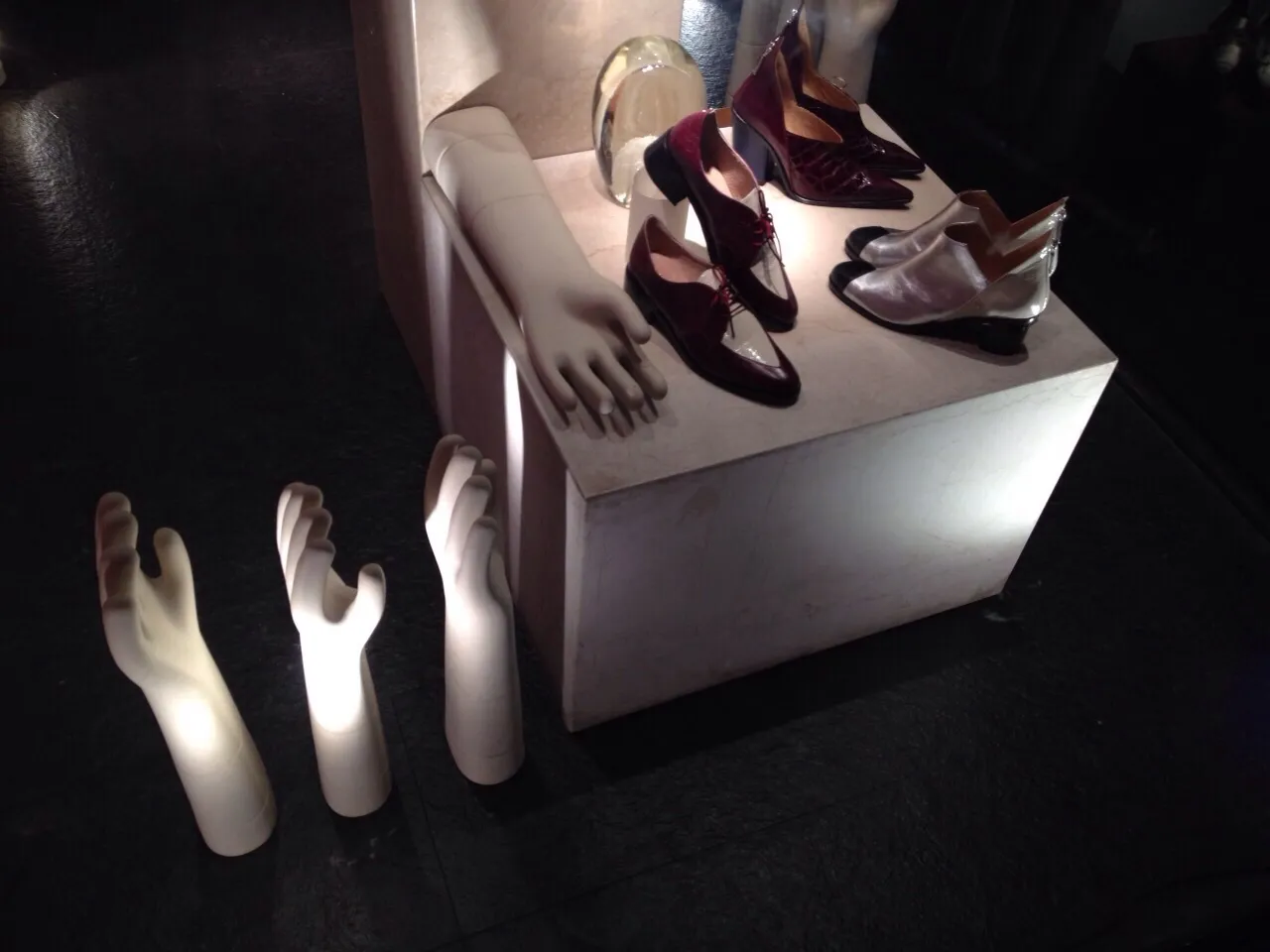 manos de exhibición con zapatos antiguos sobre pedestal iluminado