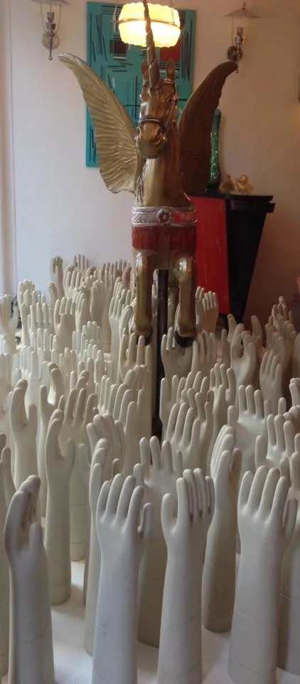 Scultura antica in ceramica di mani bianche intorno a un unicorno dorato