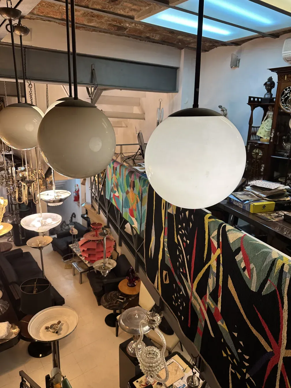 Cinque lampade sospese antiche con design sferico in un ambiente decorativo.